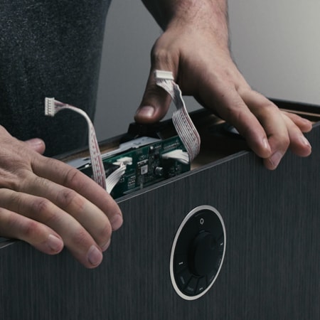 Hands holding Ruark Audio R5 MiE’s cabinet